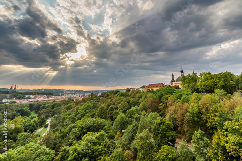 View of Prague taken from Nuselsky bridge on sunset captures typical local architecture from aerial perspective. Famous Vysehrad castle is behind it.