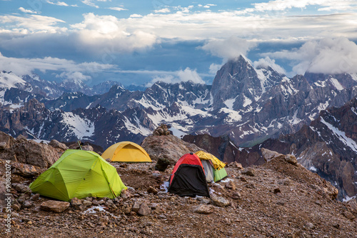 Camping Tents and High Mountain View Twilight Panorama of Fan Mountains Valley with Alpine Camp on Rock Moraine Foreground 