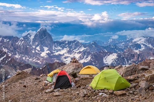 Camping Tents and High Mountain View Twilight Panorama of Fan Mountains Valley with Alpine Camp on Rock Moraine Foreground