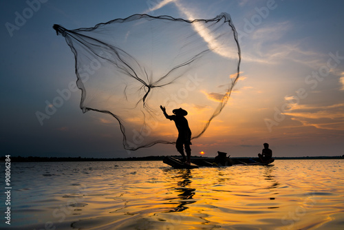 фотографія Silhouette of a fisherman throwing his net with sunset.