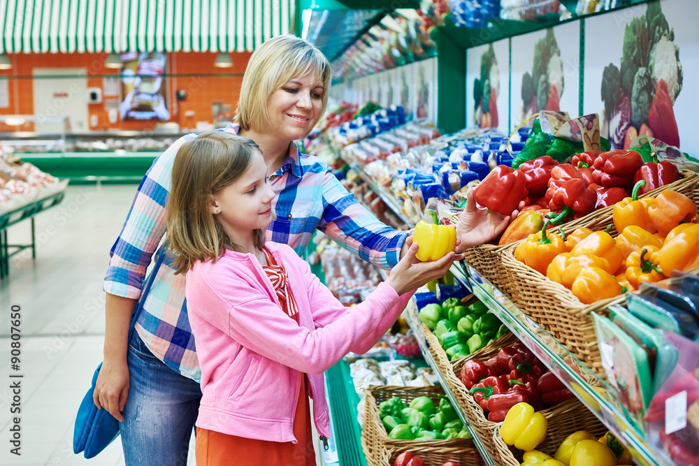Mother and daughter chooses bell peppers in supermarket