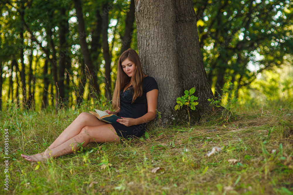 woman girl sits reading a book under a tree in the forest park o