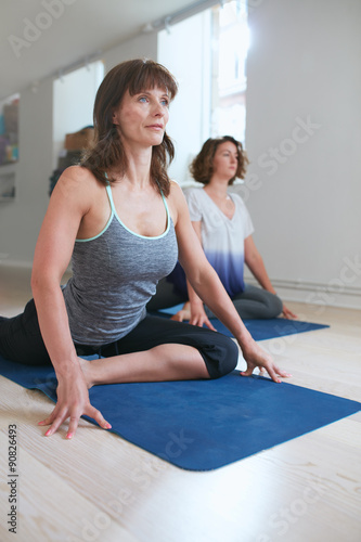 Women at yoga class practicing pigeon pose