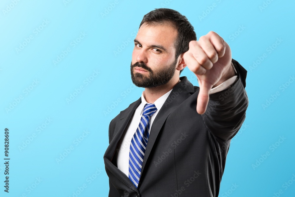 Young businessman with his thumb down over white background Young businessman with his thumb down over white background