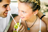 Happy young gorgeous couple is smiling drinking juice and looking at each other