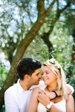 Young happy beautiful wedding couple in white dresses is hugging kissing in the park in summer