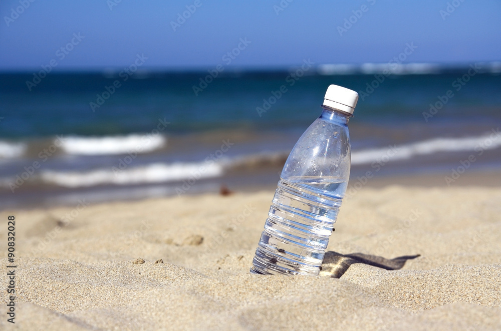 Drinking water in bottle on sand on beach Drinking water in bottle on sand on beach