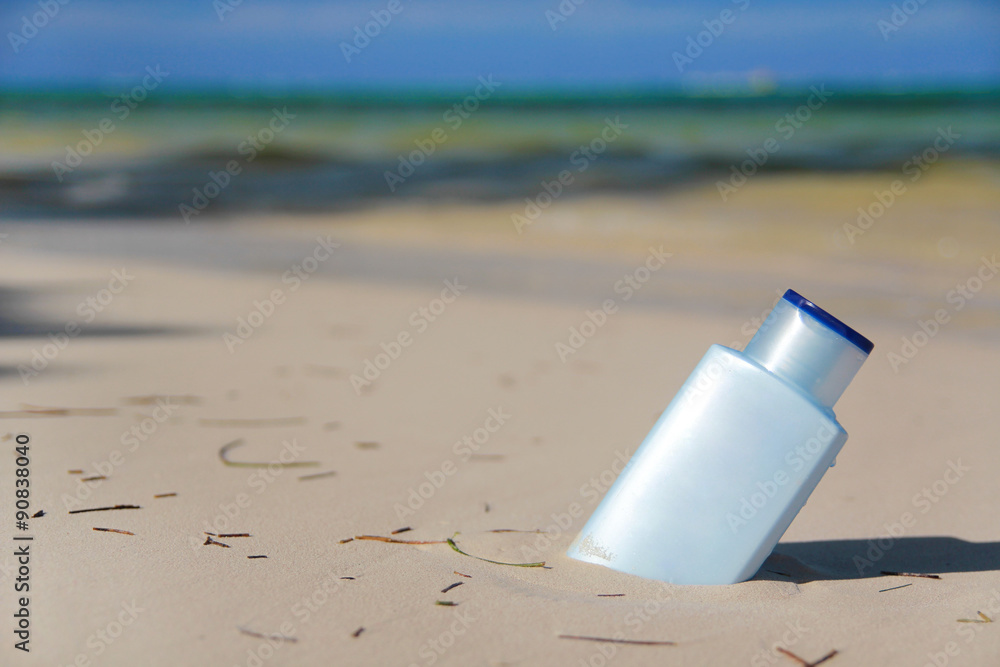 Blue bottle with Sunblock lotion in sand on tropical beach Blue bottle with Sunblock lotion in sand on tropical beach