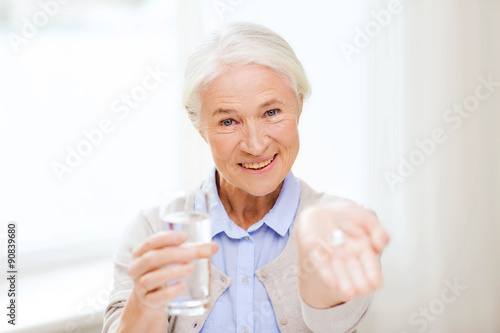 happy senior woman with water and medicine at home