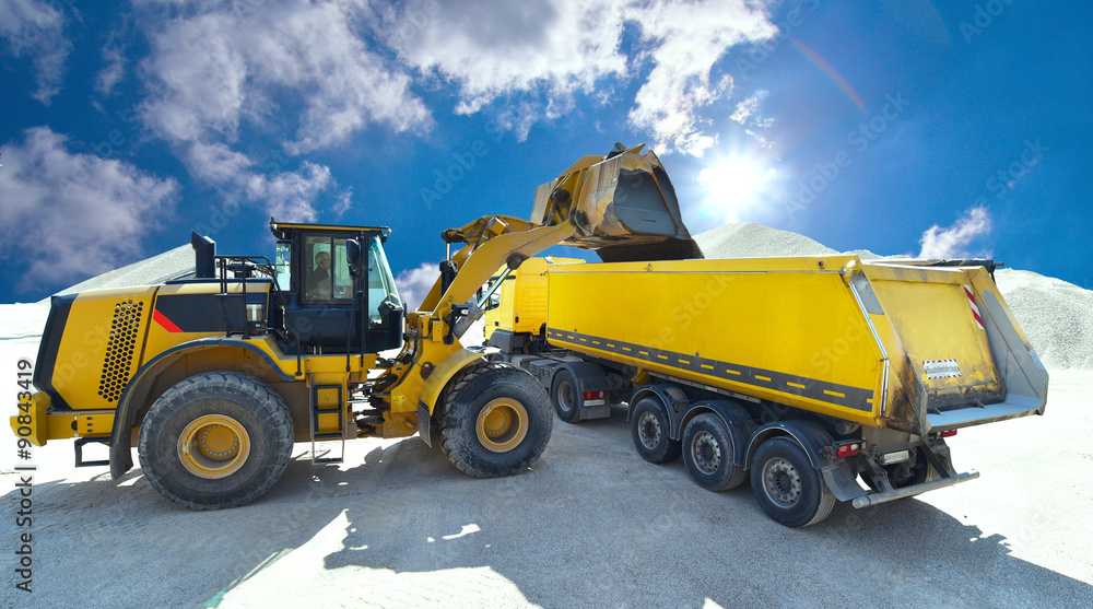 Radlader belädt LKW mit Baumaterial in einem Kieswerk // excavator loads trucks with construction material in a gravel pit