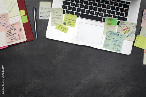 Office desk with laptop covered by post it papers