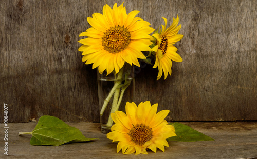 a bouquet of sunflowers in a glass on a wooden background