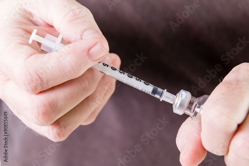 Syringe drawing insulin from vial