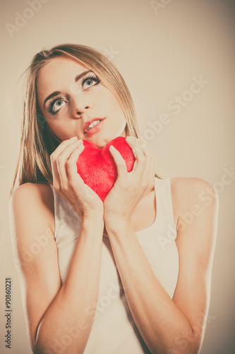 Sad unhappy woman holding red heart pillow