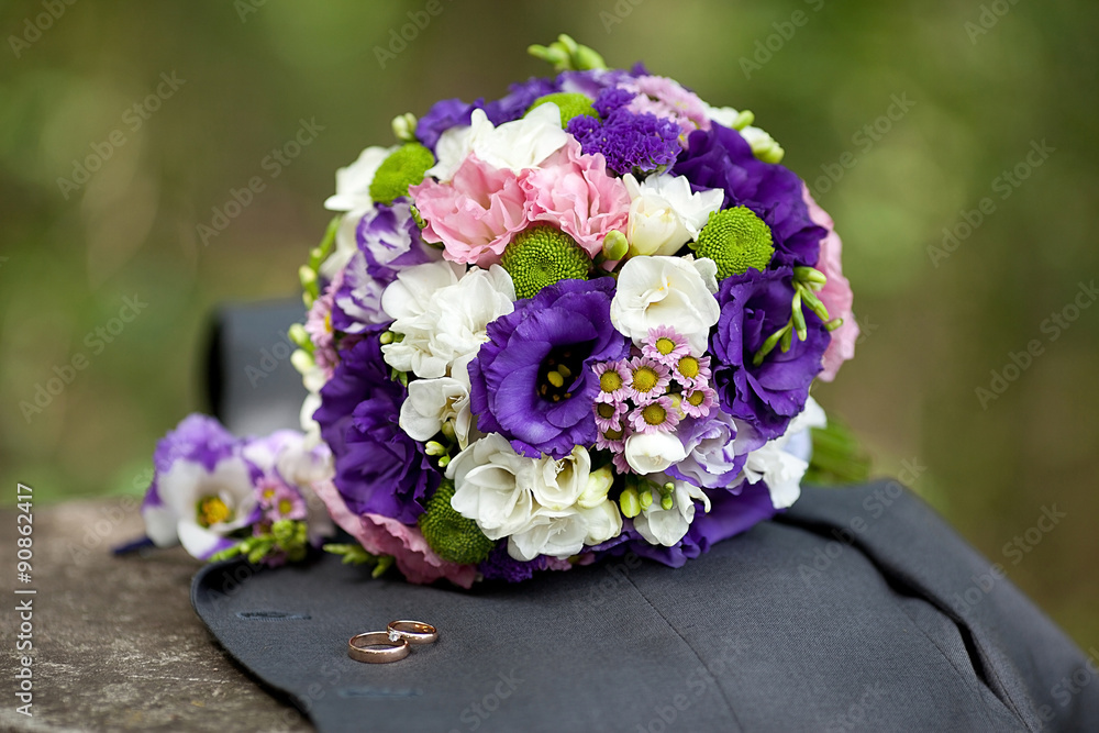 Wedding bouquet of eustomas lying on the jacket with rings