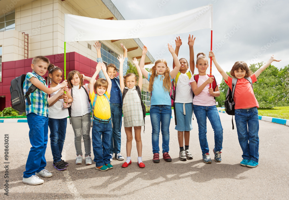 Obraz premium Group of happy children with arms up hold placard
