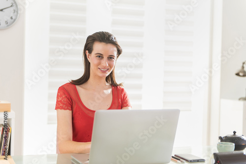 Looking at camera a modern businesswoman works on a laptop Free Download Looking at camera a modern businesswoman works on a laptop - GFXLoad