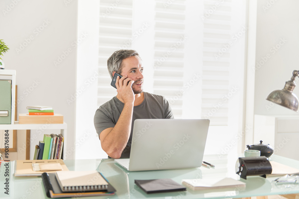 man at phone sitting at office working on his laptop man at phone sitting at office working on his laptop