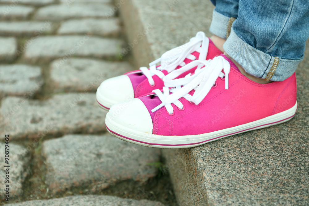 Female feet in pink gumshoes on stone stairs