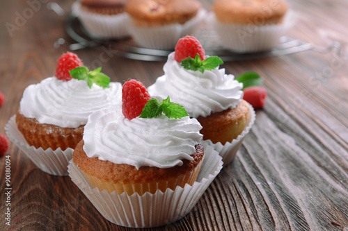 Delicious cupcakes with berries and fresh mint on wooden table close up