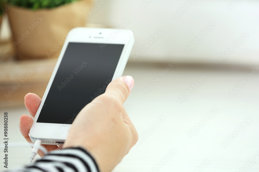 Music smartphone in female hand, on light background