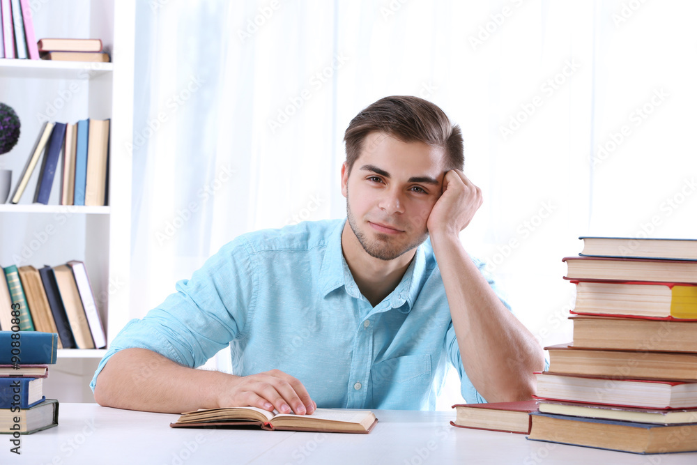 Young man reading book at table in room Young man reading book at table in room
