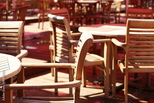 Wooden chairs and tables on summer restaurant terrace