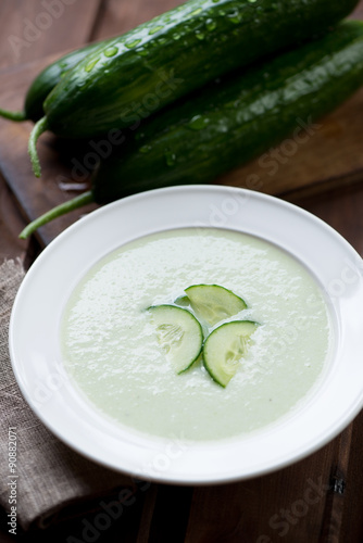 Closeup of cucumber cream-soup in a glass plate, selective focus