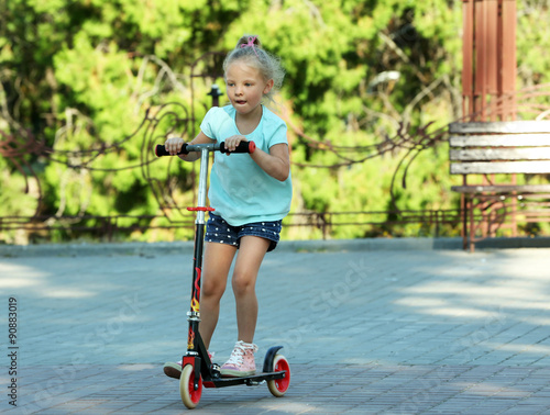 Small girl riding on scooter in park