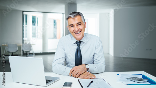 Confident businessman posing at desk