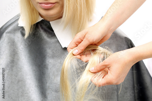 Zagęszczanie włosów.Fryzjer przedłuża włosy dopinając pasma włosów