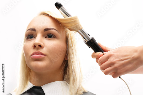 Modelowanie włosów na lokówkę.Kobieta w salonie fryzjerskim, fryzjer kręci włosy na lokówkę.