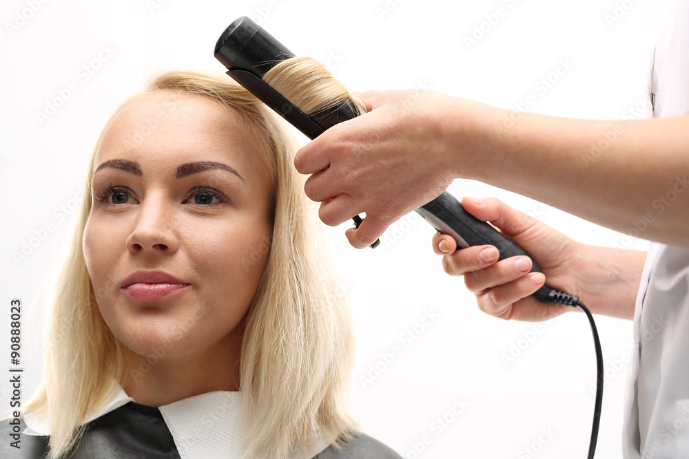 Fototapeta premium Kobieta u fryzjera.Kobieta w salonie fryzjerskim, fryzjer kręci włosy na lokówkę.