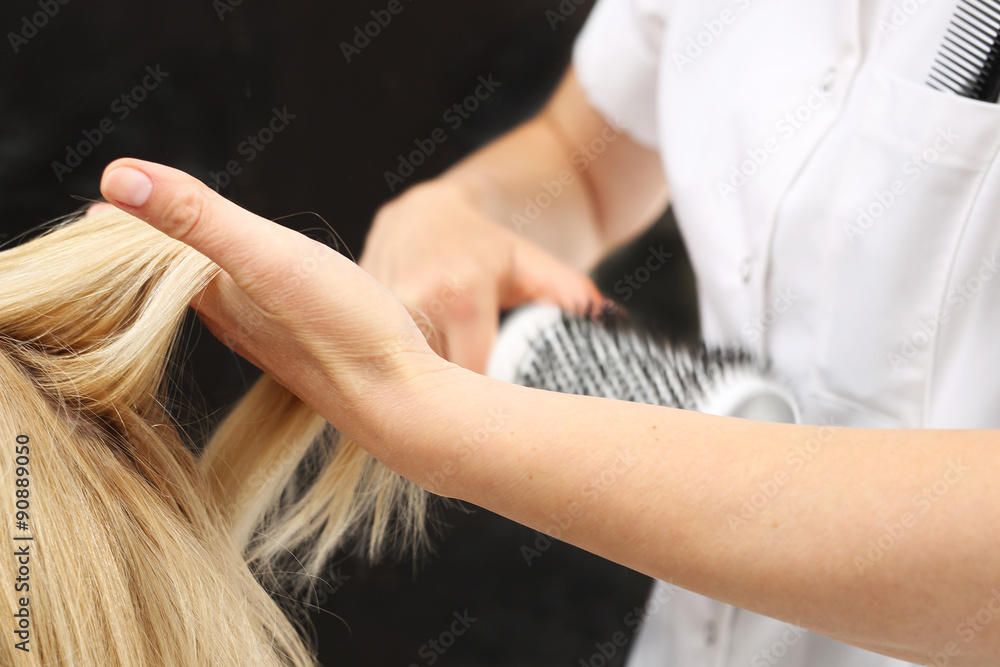 Obraz premium Kobieta u fryzjera, fryzjer modeluje włosy na okrągłej szczotce
