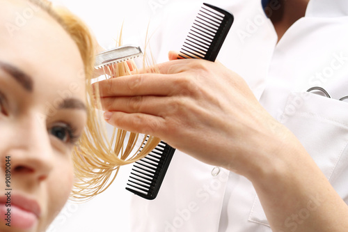 Fryzjer strzyże kobietę nożem chińskim w salonie fryzjerskim