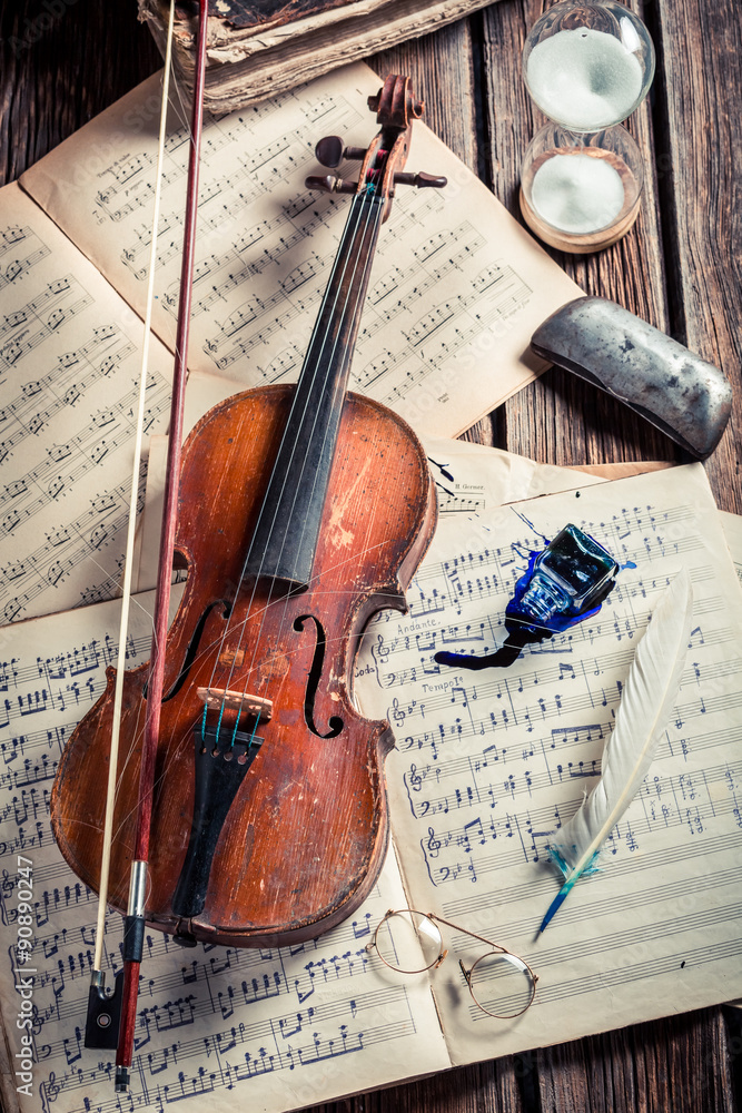 Naklejka premium Retro violin and musical sheets on old wooden table
