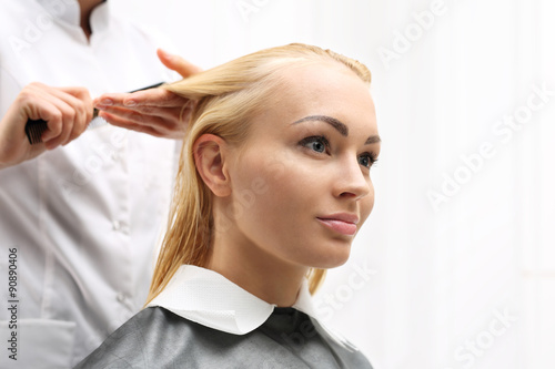 Fryzjer.Kobieta na fotelu fryzjerskim podczas zabiegu stylizacji włosów