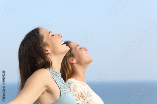 Two girls breathing deep fresh air on the beach