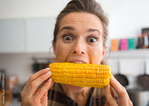 Φωτογραφία Teasing, happy woman taking big bite of corn on the cob