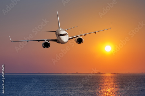 Passenger airplane flying on sunset