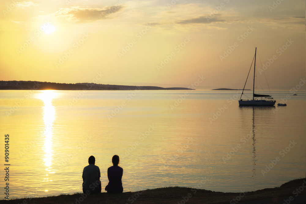 backlit couple admiring the sunrise over the sea