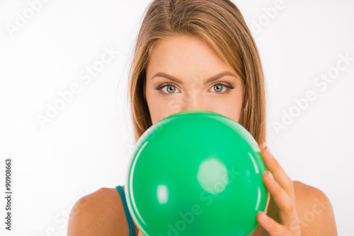 Attractive girl with green eyes inflating a balloon