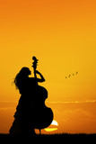 woman plays the double bass at sunset