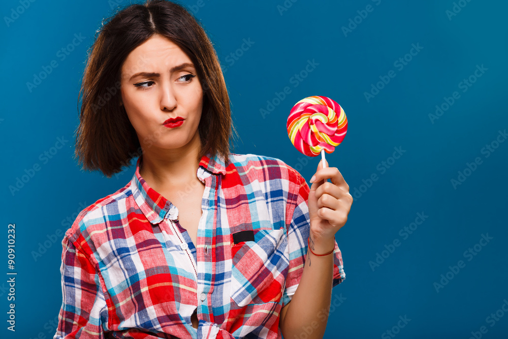 Attractive brunette girl posing with colored candy in studio