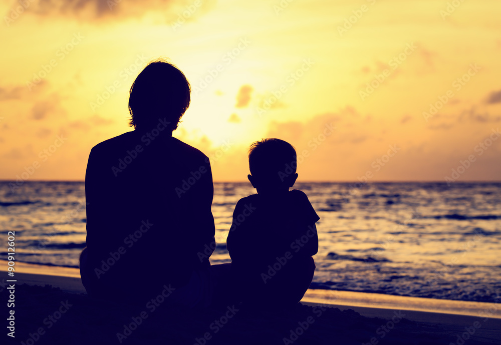 father and little son looking at sunset on beach - obrazy, fototapety, plakaty 