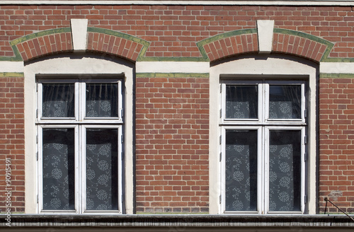 Twin windows. Fancy brickwork and alternating colours take ordinary functional windows on to a more decorative level. Simple floral net curtains complete the design.