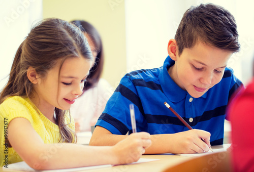 group of school kids writing test in classroom