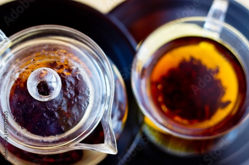 Strong black tea in glass cup and teapot on vinyl record discs. Selective focus on teapot © azamotkin