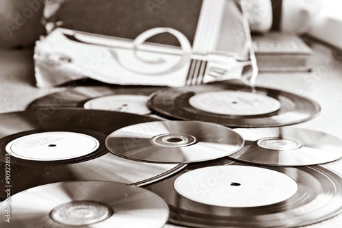 Black and white composition with blurred background with vinyl records and CD. Focus on central part of image