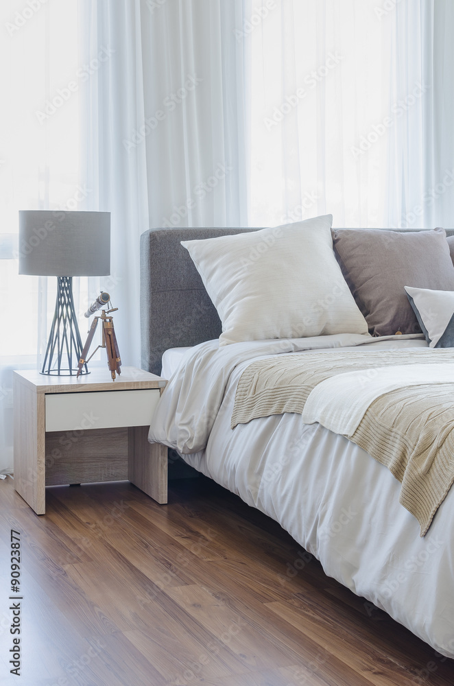 pillows on modern bed with grey lamp on wooden table side